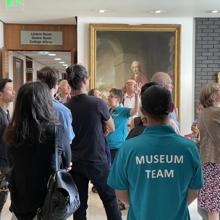 A Tour Group Listenign To A Guide At The RCP