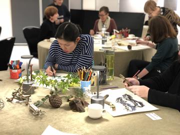 A woman draws a group of plants at a drawing workshop