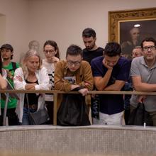 A tour group leans over a brass banister in the RCP